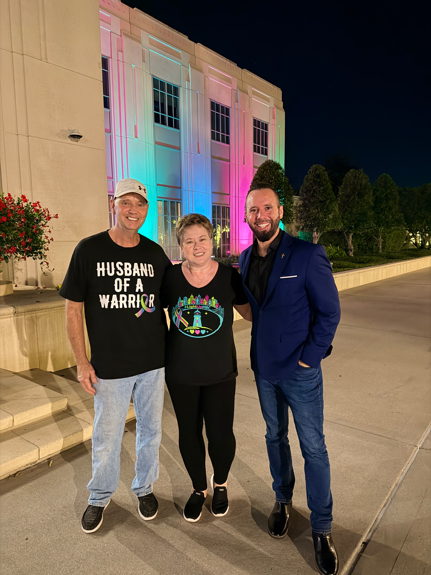 Austin Arthur with neighbors in front of Winter Garden City Hall lit in green, teal, and pink for Light Up MBC