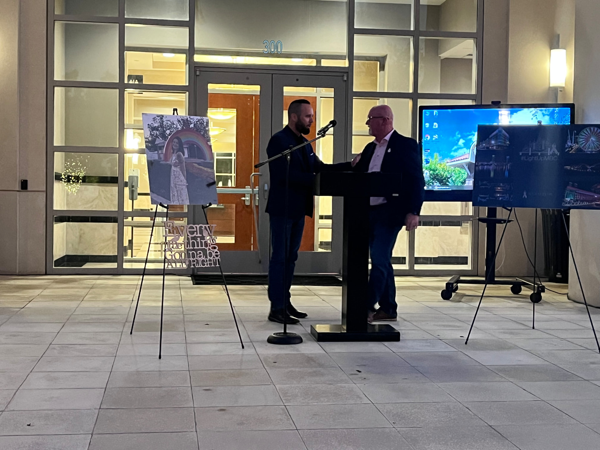 Austin Arthur shaking hands with Dave Buckles on stage at the Light Up MBC ceremony at Winter Garden City Hall