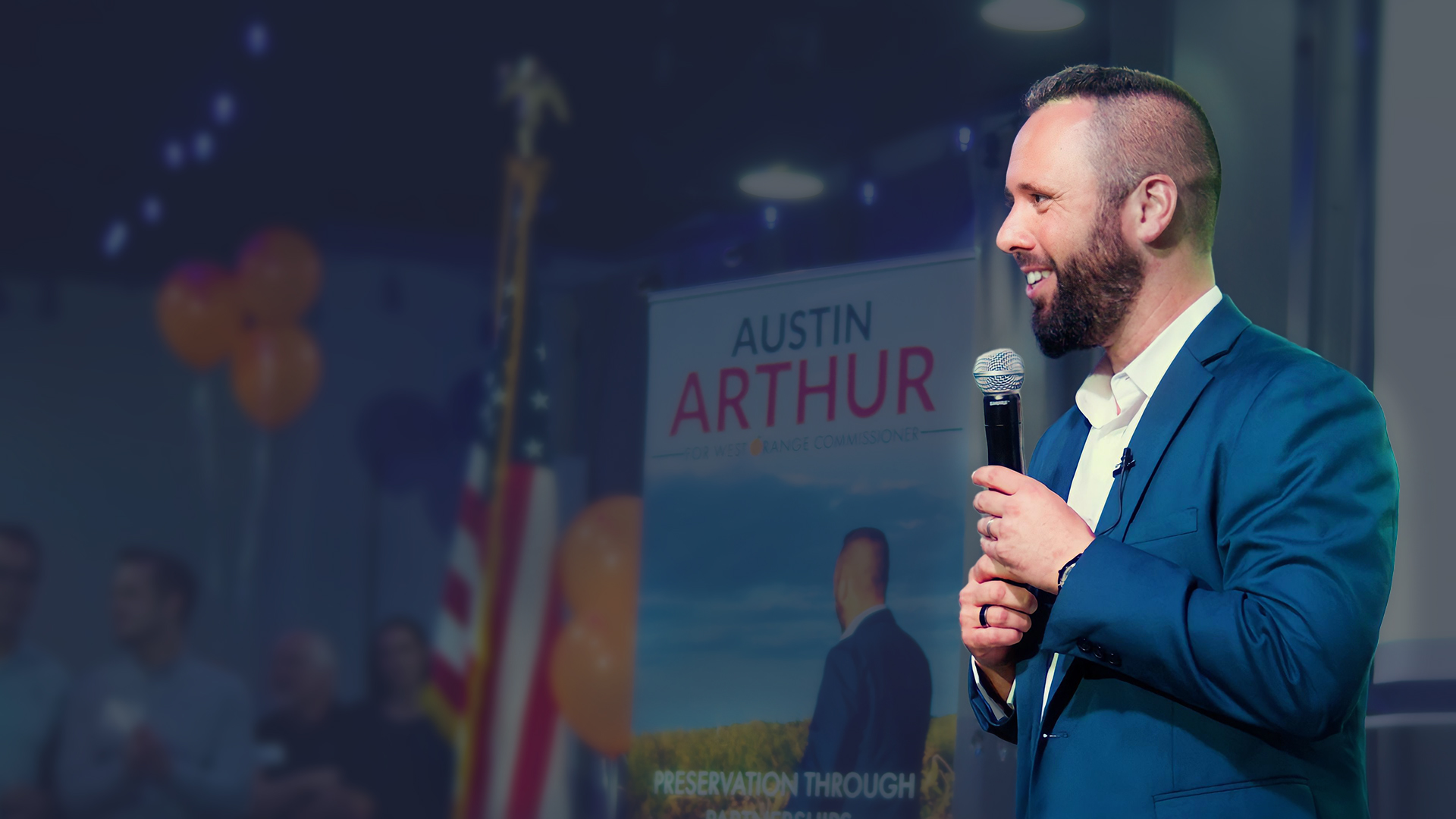 Austin Arthur on stage with the campaign banner behind him