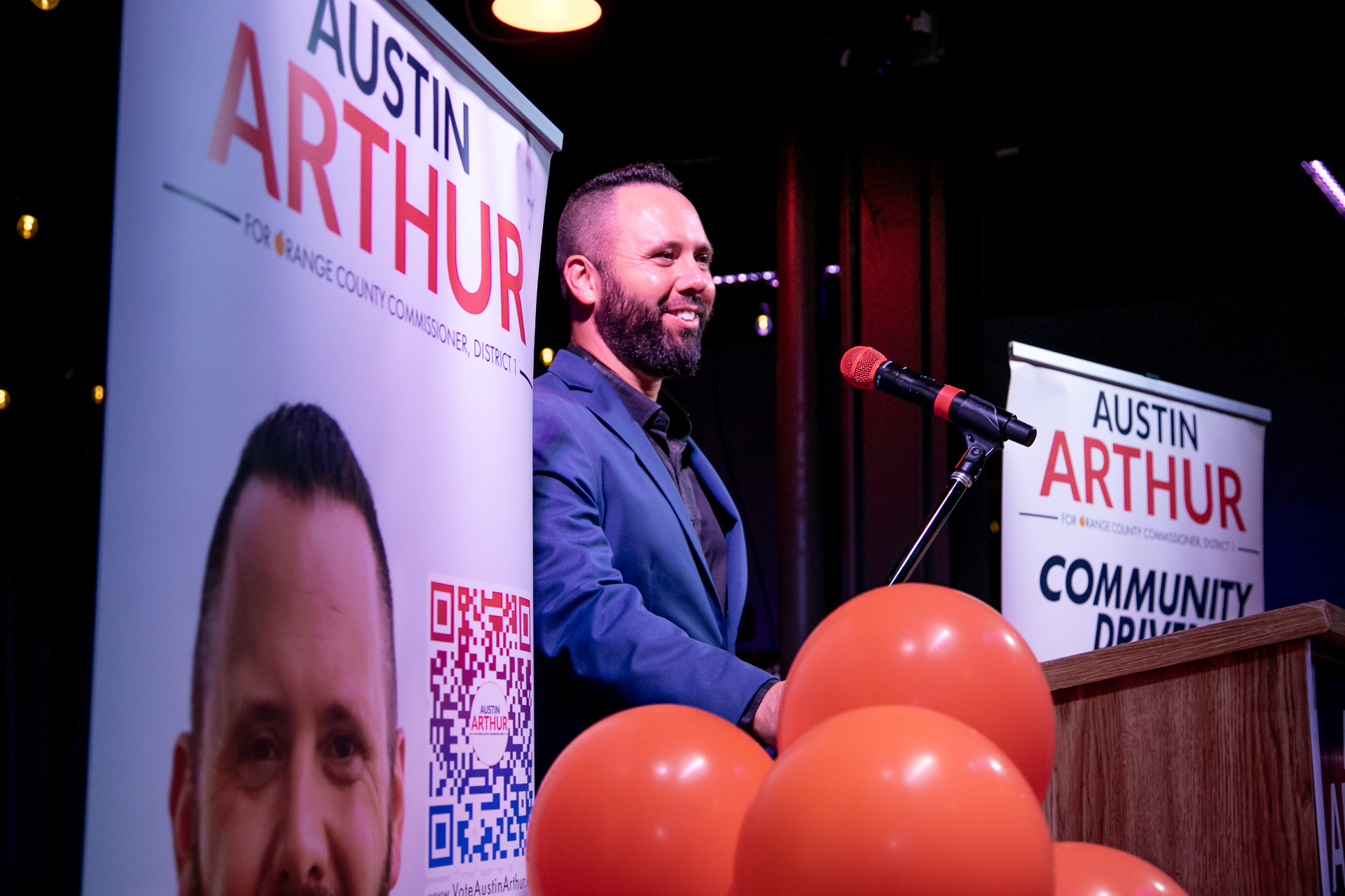 Austin Arthur at the podium with community-driven signage