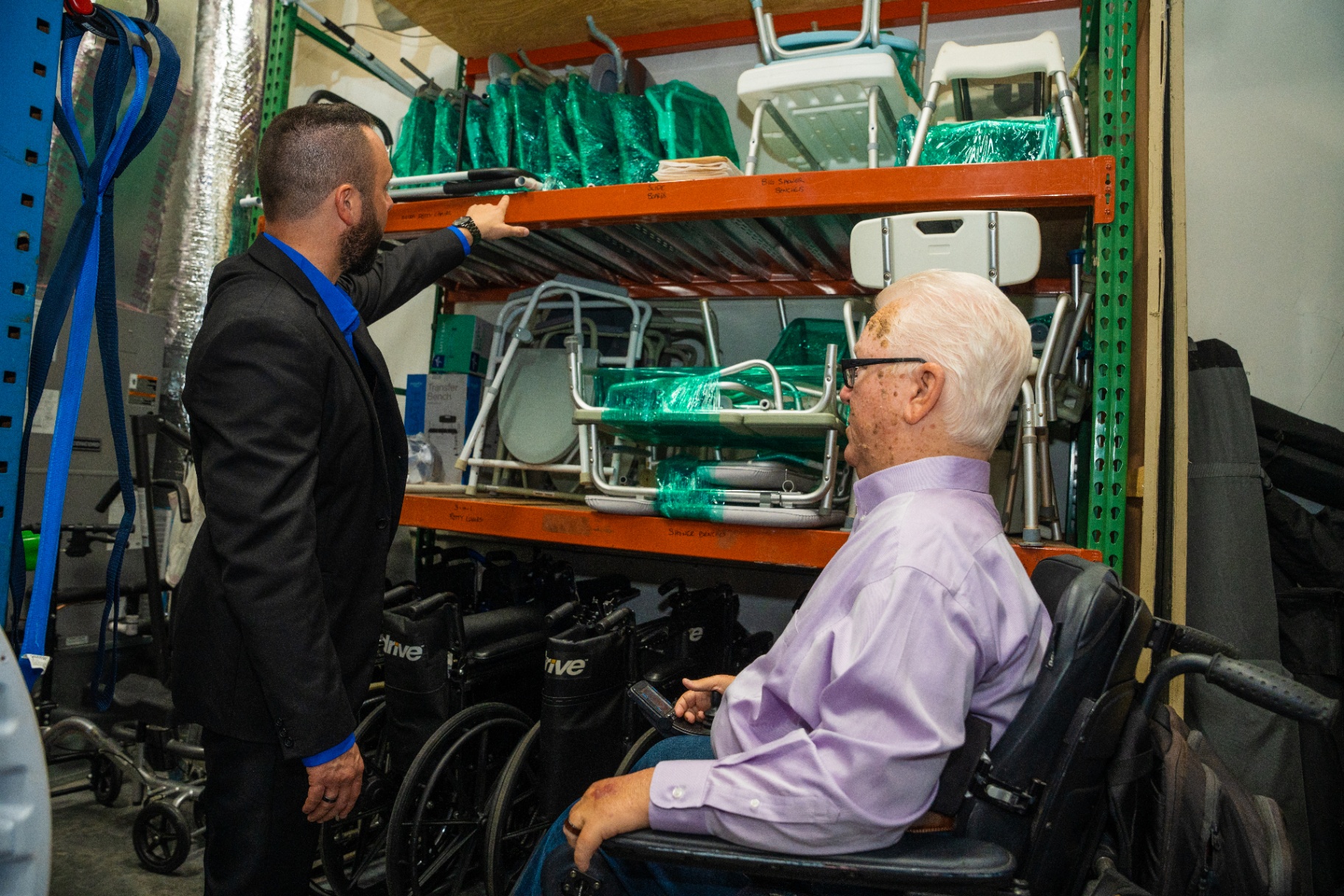 Austin Arthur touring a medical equipment facility with a senior resident in a wheelchair