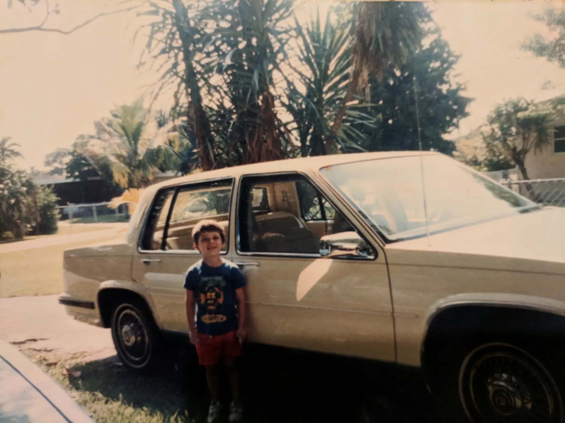 Austin Arthur as a young boy standing beside the family car outside his childhood home in Miami, Florida