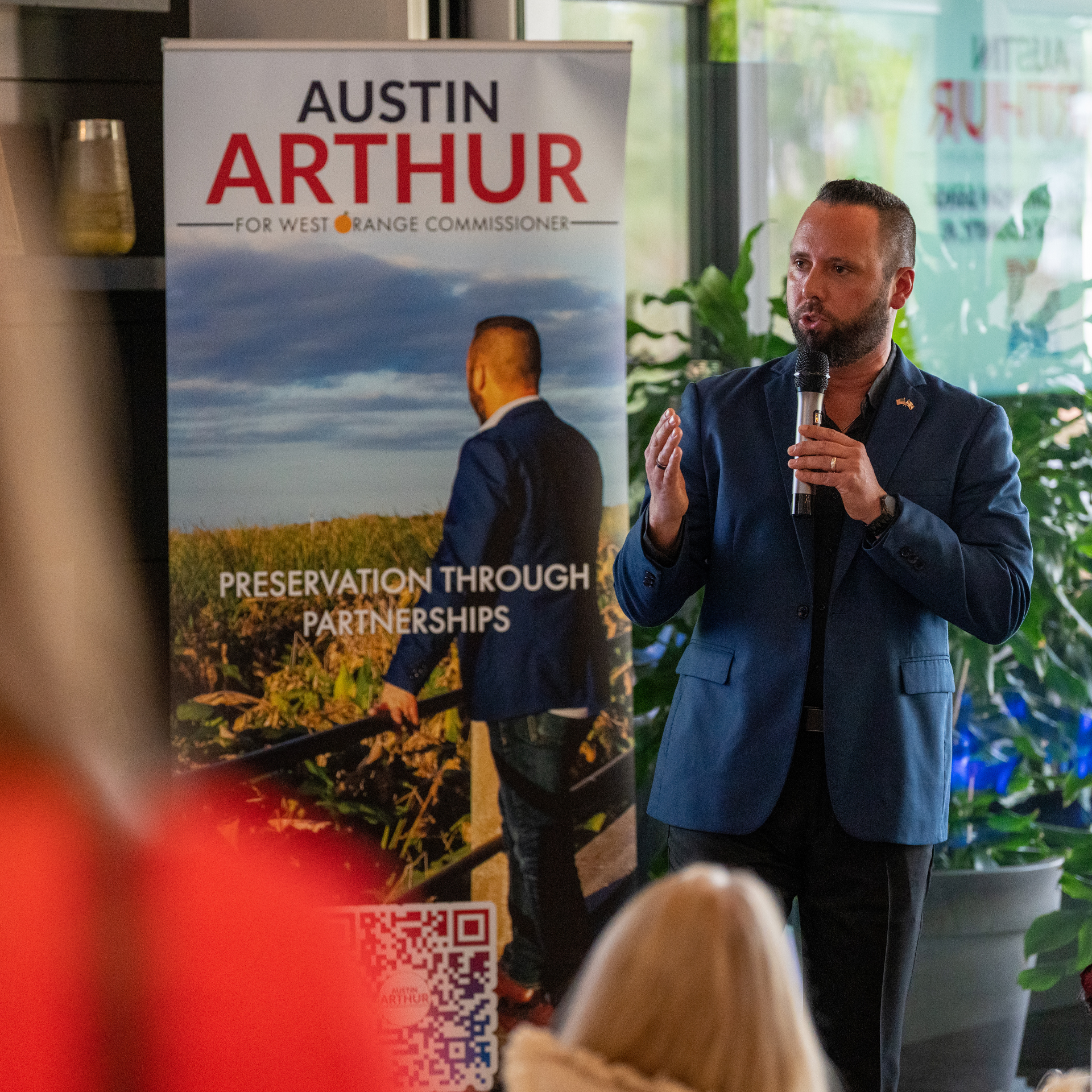 Austin Arthur speaking to supporters, 'Preservation Through Partnerships' banner behind him